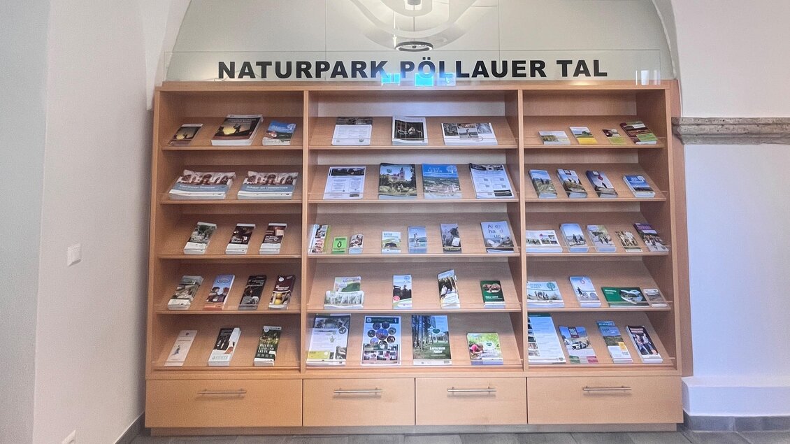 Ein Informationsstand mit zahlreichen Broschüren über den Naturpark Pöllauer Tal. Die Regale sind gut organisiert und bieten eine Übersicht zu verschiedenen Themen des Parks. | © Tourismusverband Oststeiermark
