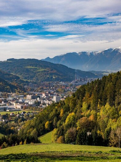 A picturesque landscape with mountains and dense forests. The town is located in the valley and is surrounded by colorful trees. | © TV ERZBERG LEOBEN