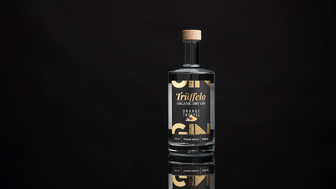 Eine elegante Flasche Trüffel-Gin steht vor einem schwarzen Hintergrund. Die Flasche hat ein modernes Design mit einer goldenen Schrift. | © True-fellow Handel GmbH