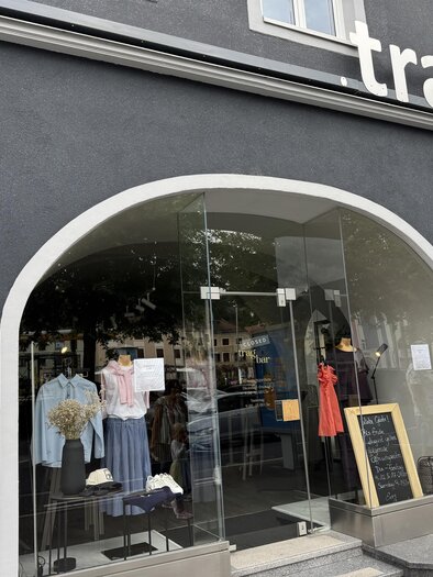 A fashion store with a large window front. It displays various garments and accessories in the showcase. | © TV Hochsteiermark