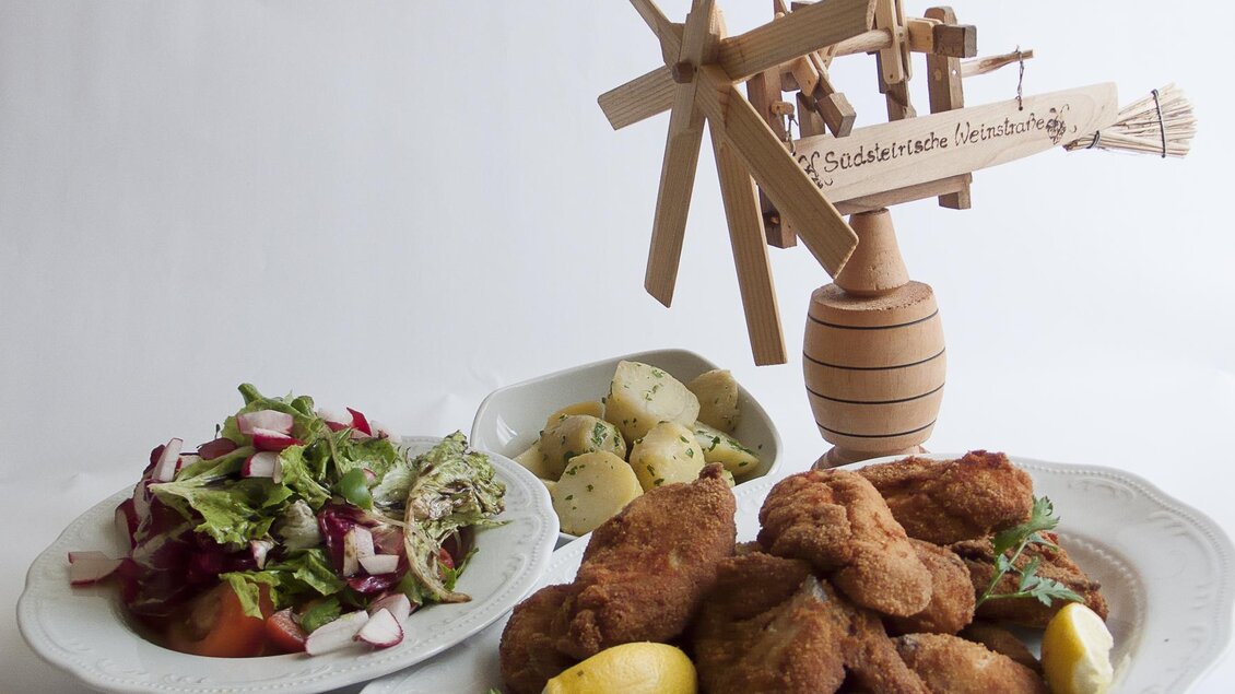 Ein Teller mit knusprigen Fischfrikadellen, frischen Kräutern und Zitronenscheiben. Daneben befindet sich ein bunten Salat und gekochte Kartoffeln. | © Tscheppe