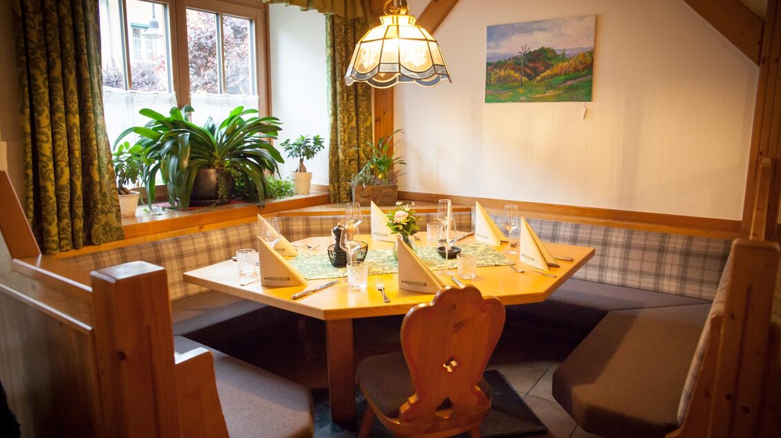 Ein gemütlicher Essbereich mit einem runden Tisch und Bänken. Der Tisch ist liebevoll gedeckt und mit Pflanzen dekoriert. | © Tscheppe