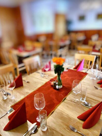 Ein einladendes Restaurant mit gedeckten Tischen. Rote Servietten und Blumen in der Mitte schaffen eine gemütliche Atmosphäre. | © Ungerhof