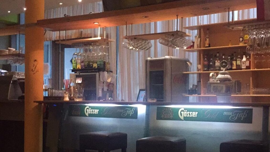 Eine moderne Bar mit beleuchtetem Tresen und Stühlen. Im Hintergrund sind Regale mit Getränken und ein Fernseher zu sehen. | © VAZ Niklasdorf