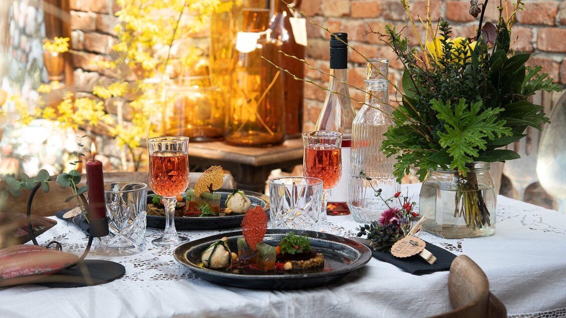 Ein schön gedeckter Tisch mit köstlichen Speisen und Getränken. Im Hintergrund sind Pflanzen und eine Ziegelmauer zu sehen. | © Vom Hügel