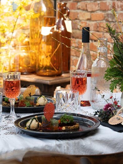 Ein schön gedeckter Tisch mit köstlichen Speisen und Getränken. Im Hintergrund sind Pflanzen und eine Ziegelmauer zu sehen. | © Vom Hügel