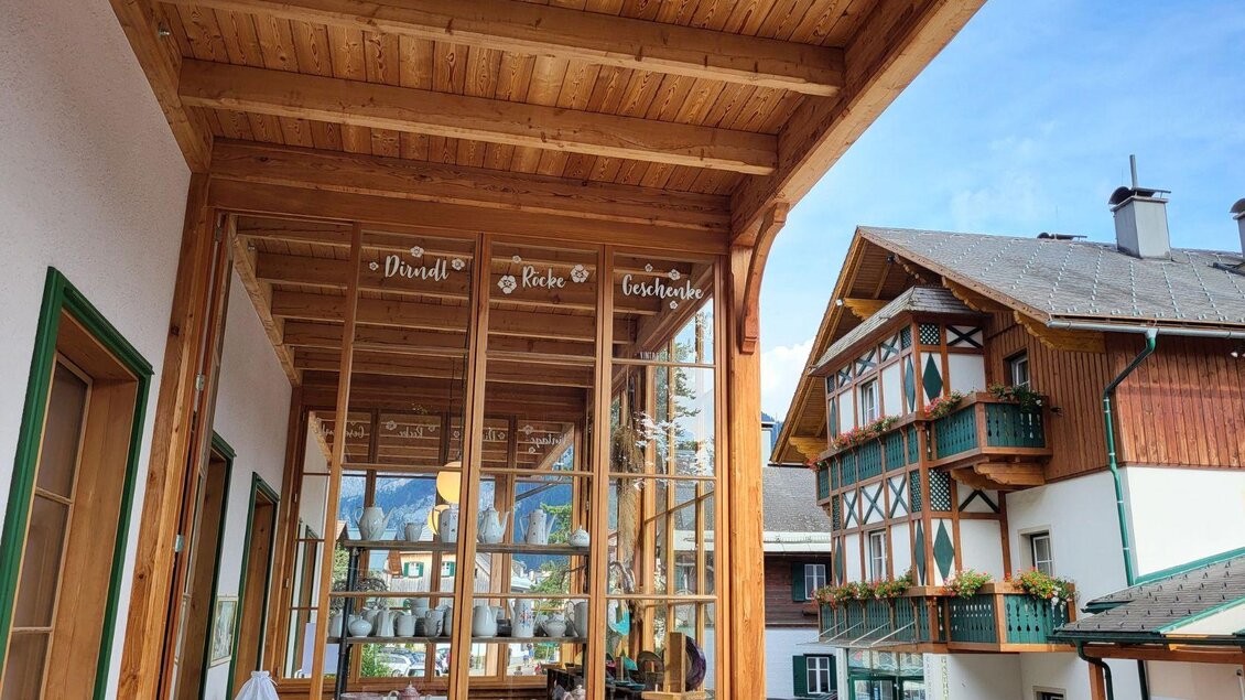 Ein traditionelles Holzgebäude mit einem dekorativen Eingangsbereich. Im Hintergrund sind weitere bayerische Architecturelemente zu sehen. | © Petra Kirchschlager