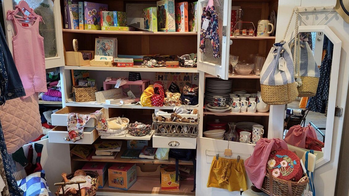 Ein gemütlicher Raum mit einem großen Schrank voller bunter Kleidung und Accessoires. Auf den Regalen stehen auch Geschirr und Dekorationsgegenstände. | © Petra Kirchschlager