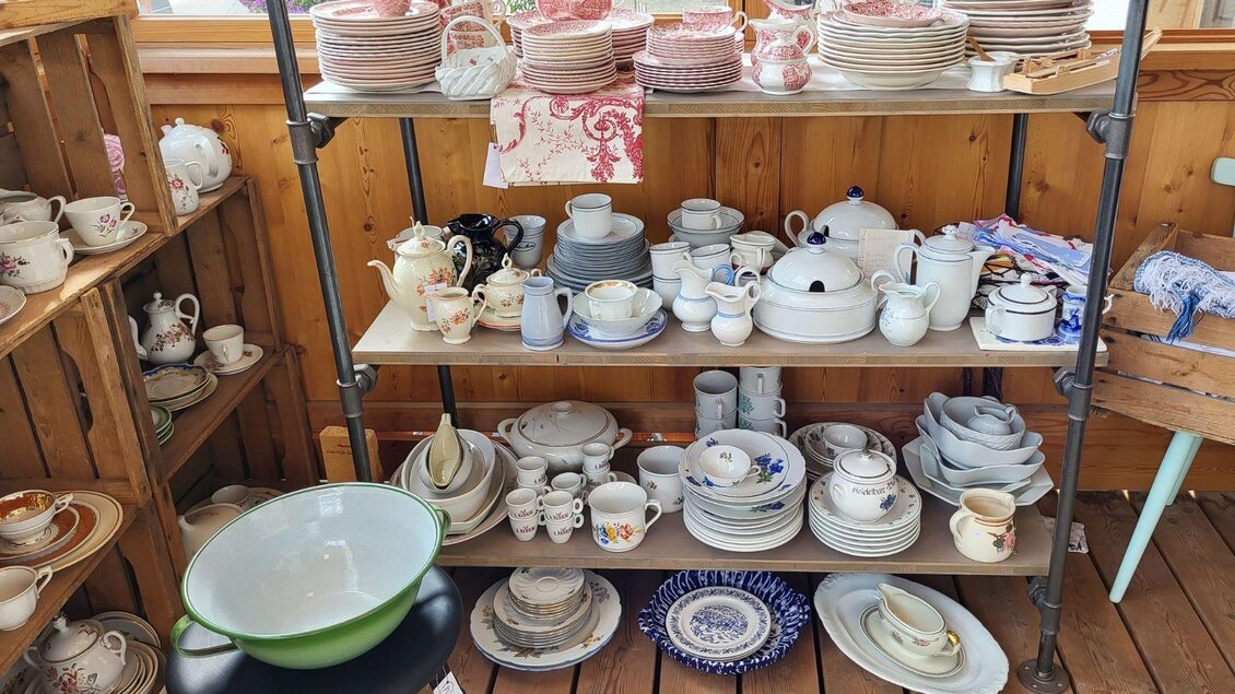 Ein Regal voller Geschirr und Porzellan. Es gibt Tassen, Teller und Schalen in verschiedenen Designs und Farben. | © Petra Kirchschlager