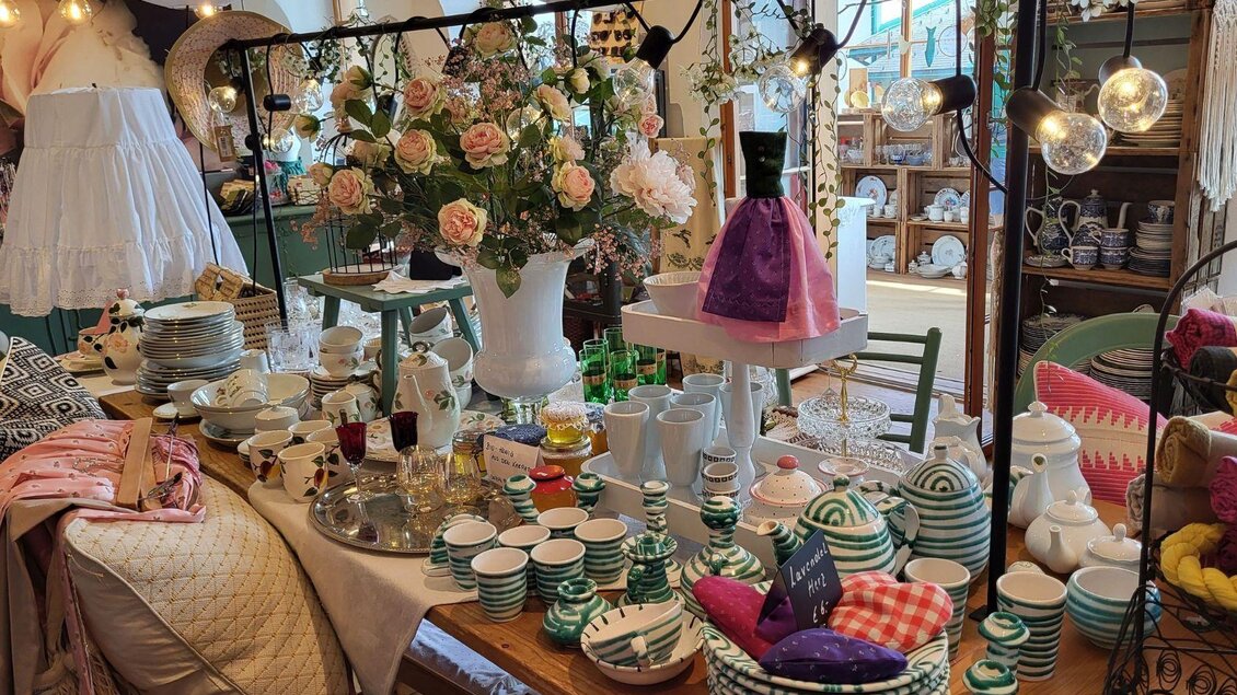 Ein schön dekorierter Tisch mit verschiedenen Geschirrstücken und einer Blumenvase. Im Hintergrund sind weitere Dekorationsartikel und Geschirr sichtbar. | © Petra Kirchschlager