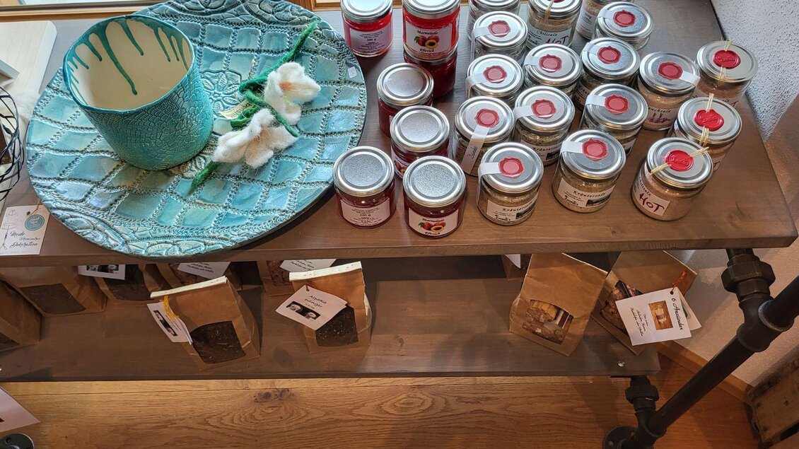 Ein Holztisch mit verschiedenen Produkten. Darauf befinden sich eine dekorative Schale, mehrere Gläser mit Deckeln und Tüten mit Inhaltsangaben. | © Petra Kirchschlager