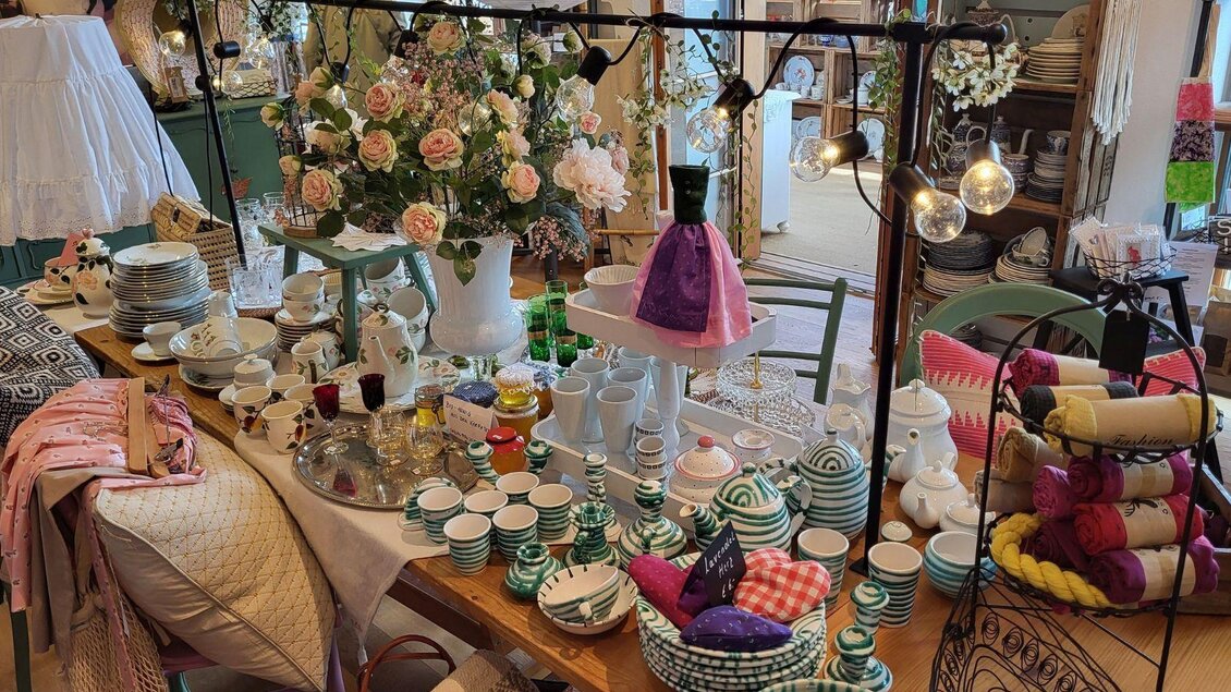 Ein geschmackvoll gedeckter Tisch mit verschiedenen Geschirrteilen und Dekoartikeln. Blumenarrangements und bunte Textilien verleihen dem Raum eine einladende Atmosphäre. | © Petra Kirchschlager