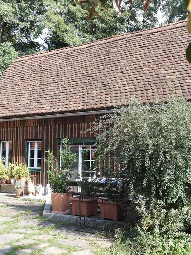 Ein gemütliches Holzhaus umgeben von Gartenpflanzen und Bäumen. Der Außenbereich hat eine unberührte, natürliche Atmosphäre. | © Vinariat Maier