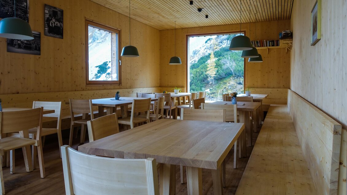Ein gemütliches Restaurant mit Holzdekor und hellen Tischen. Große Fenster bieten einen Blick ins Grüne.