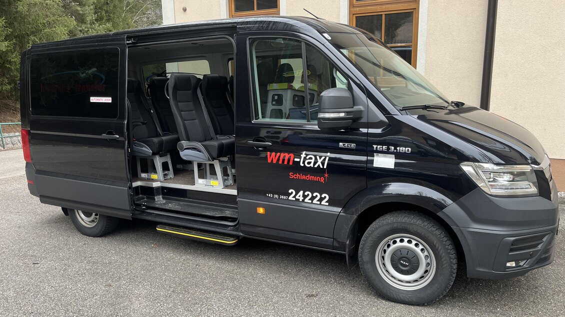 Ein schwarzer Transporter mit mehreren Sitzen an der Seite. Das Fahrzeug ist für den Personentransport ausgelegt und hat die Aufschrift "wm-taxi". | © WM Taxi Schladming GmbH