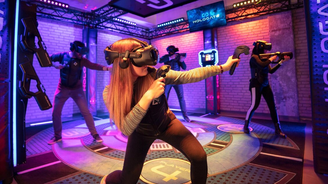 Four people wearing VR headsets playing in a darkened room with motion controllers | © WOOP!