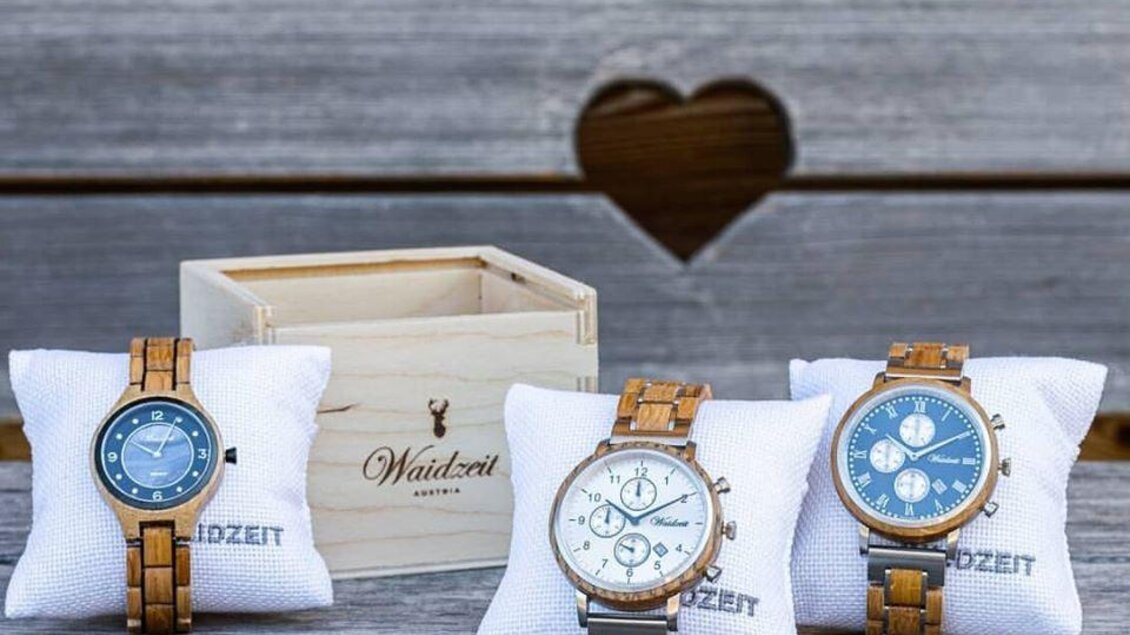 Drei elegante Uhren auf weißen Kissen, präsentiert in einer holzernen Box. Die Uhren haben verschiedene Designs und Farben. | © David Stocker