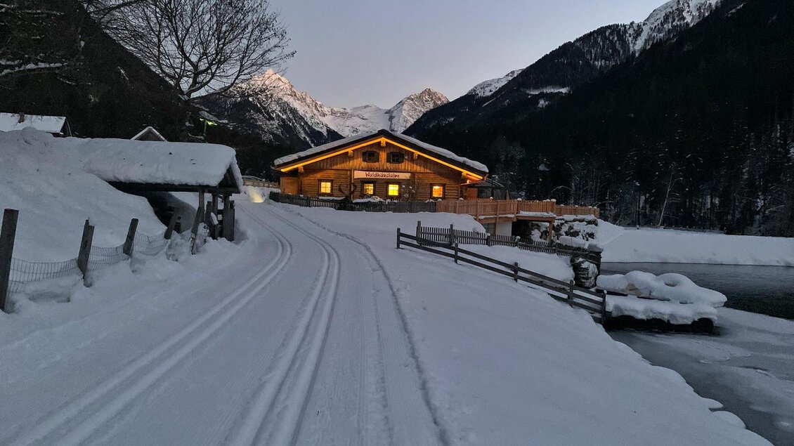 Ein Chalet im Schnee mit Bergblick und einem gefrorenen Gewässer. Die Umgebung ist ruhig und winterlich. | © Waldhäuslalm