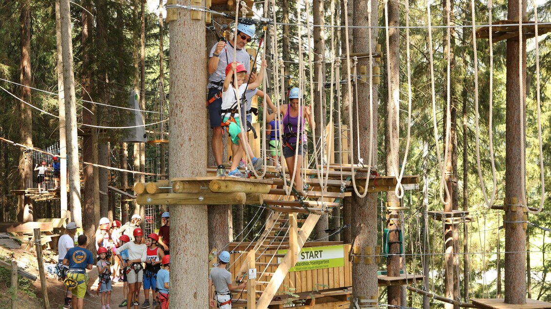 Ein Kletterpark im Wald mit mehreren Personen, die auf Plattformen und Seilrouten unterwegs sind. Es gibt ein Startschild und viele Bäume im Hintergrund. | © Hans-Peter Steiner