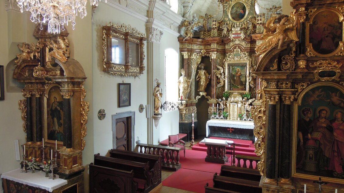 Eine prächtige Kirche mit reich verzierter Inneneinrichtung. Der Altarbereich ist kunstvoll gestaltet, und die Bänke sind aus Holz. | © TV ERZBERG LEOBEN