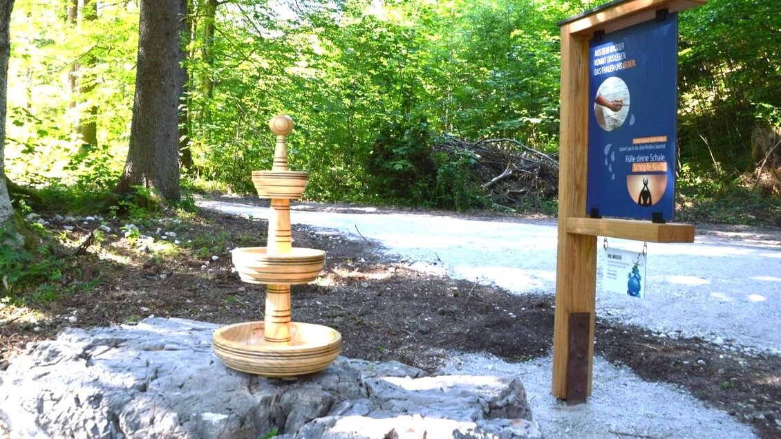 Ein Holzbrunnen steht auf einem Felsen in einem Waldgebiet. Neben dem Brunnen befindet sich ein Informationsschild. | © Zentral-Wasserversorgung Hochschwab Süd