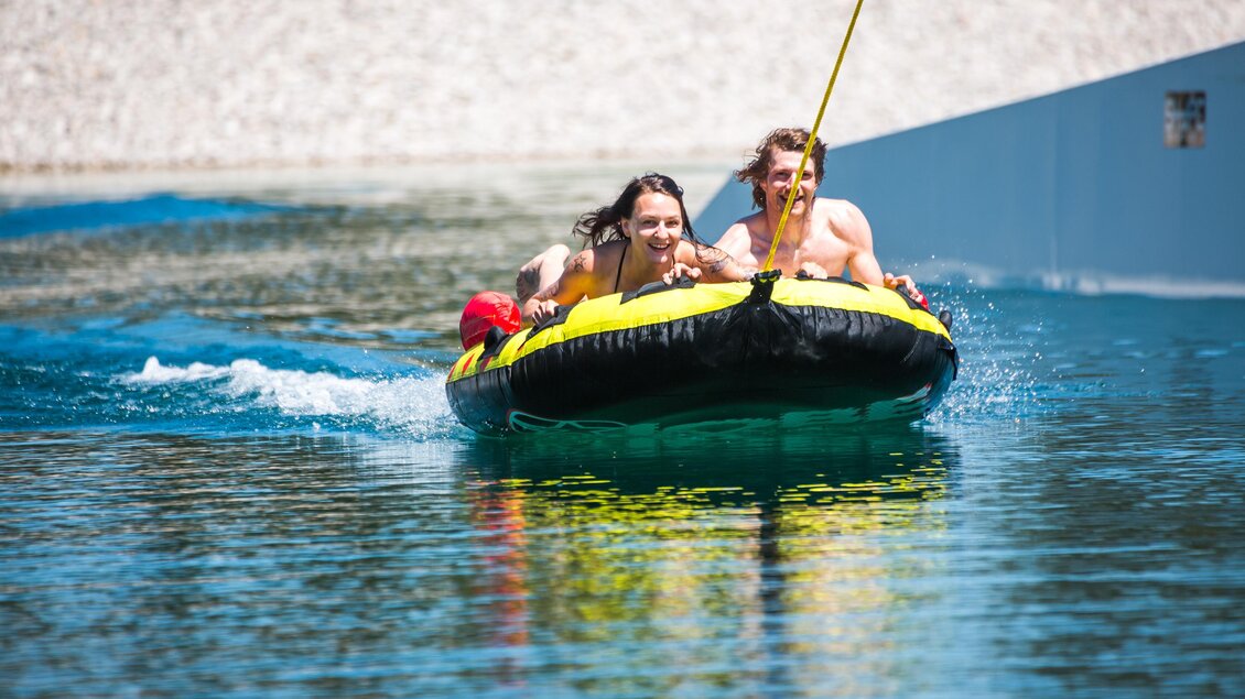 Zwei Personen fahren auf einem gelben Schlauchboot über das Wasser. Der Tag ist sonnig und das Wasser glitzert. | © www.mariazell.blog | Fred Lindmoser