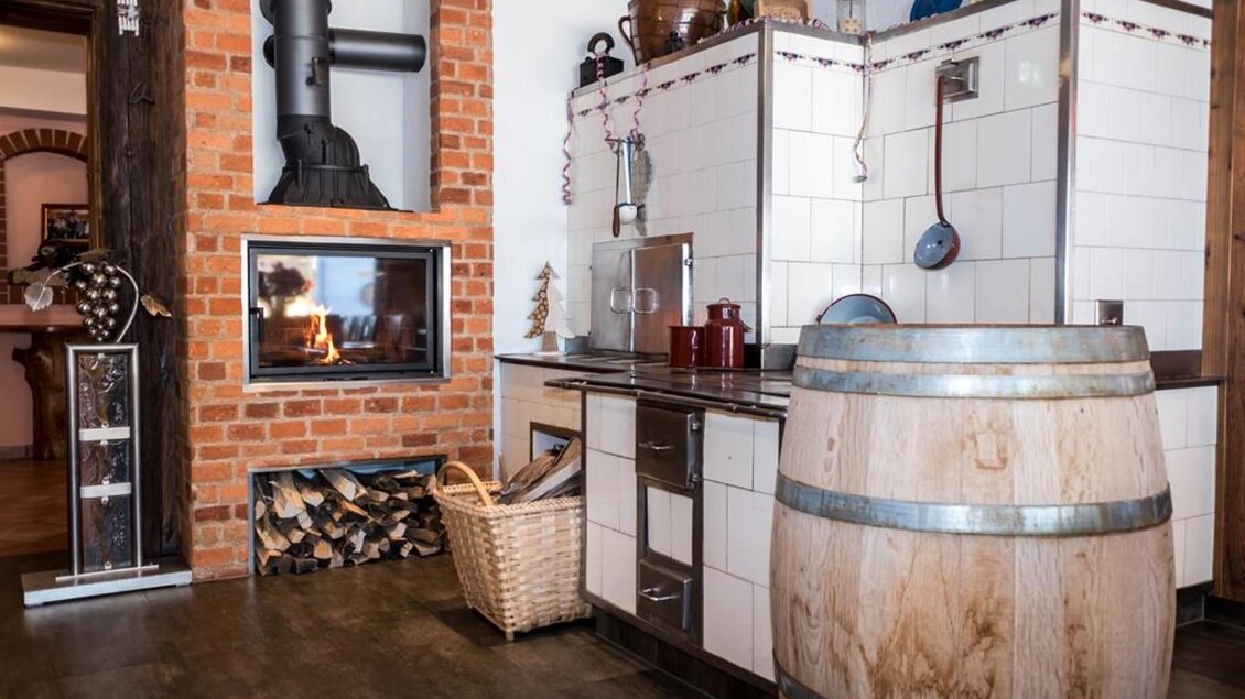 Eine moderne Küche mit einem Holzfass und einem offenen Kamin. Die Wände sind aus roten Ziegelsteinen und weißen Fliesen. | © Netwerker