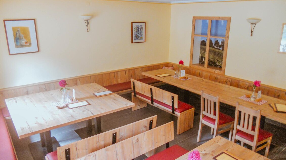 Ein gemütliches Restaurant mit Holztischen und Bänken. Die Wände sind in sanften Farben gestrichen und mit einfachen Bildern dekoriert. | © Lederer