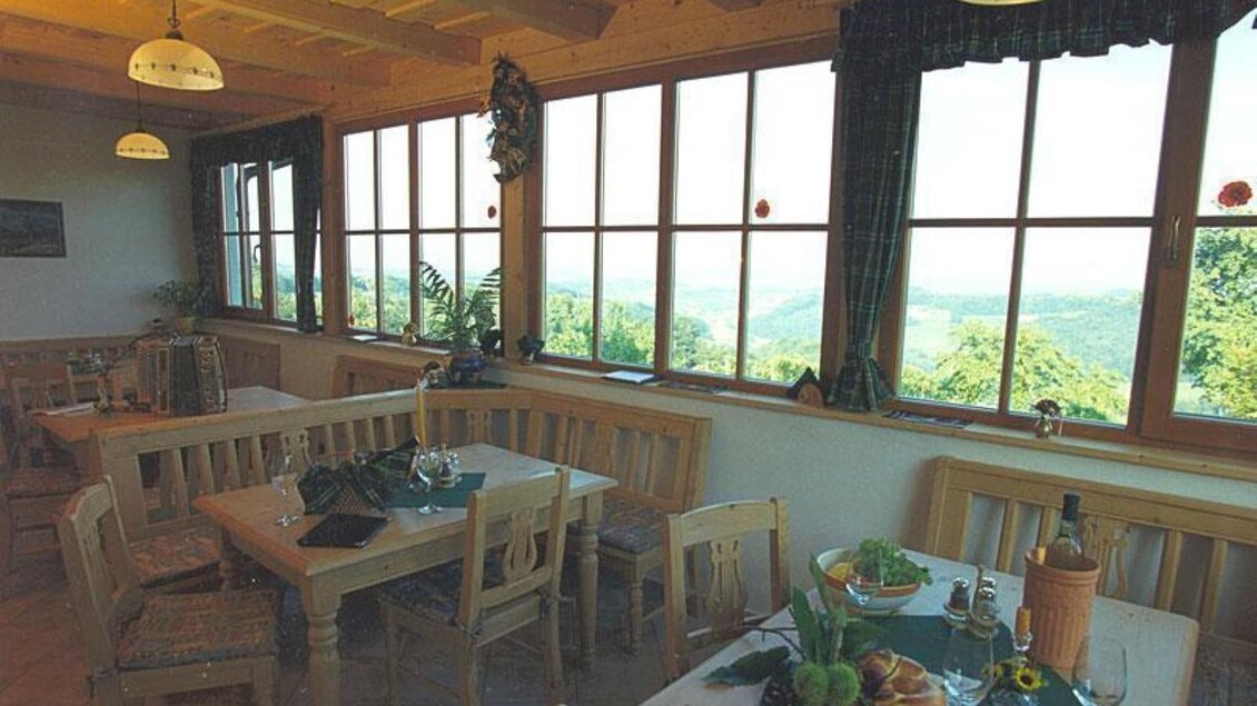 Ein gemütlicher Speisesaal mit Holztischen und Stühlen. Große Fenster bieten einen schönen Ausblick auf die Landschaft. | © Adam Schererkogl