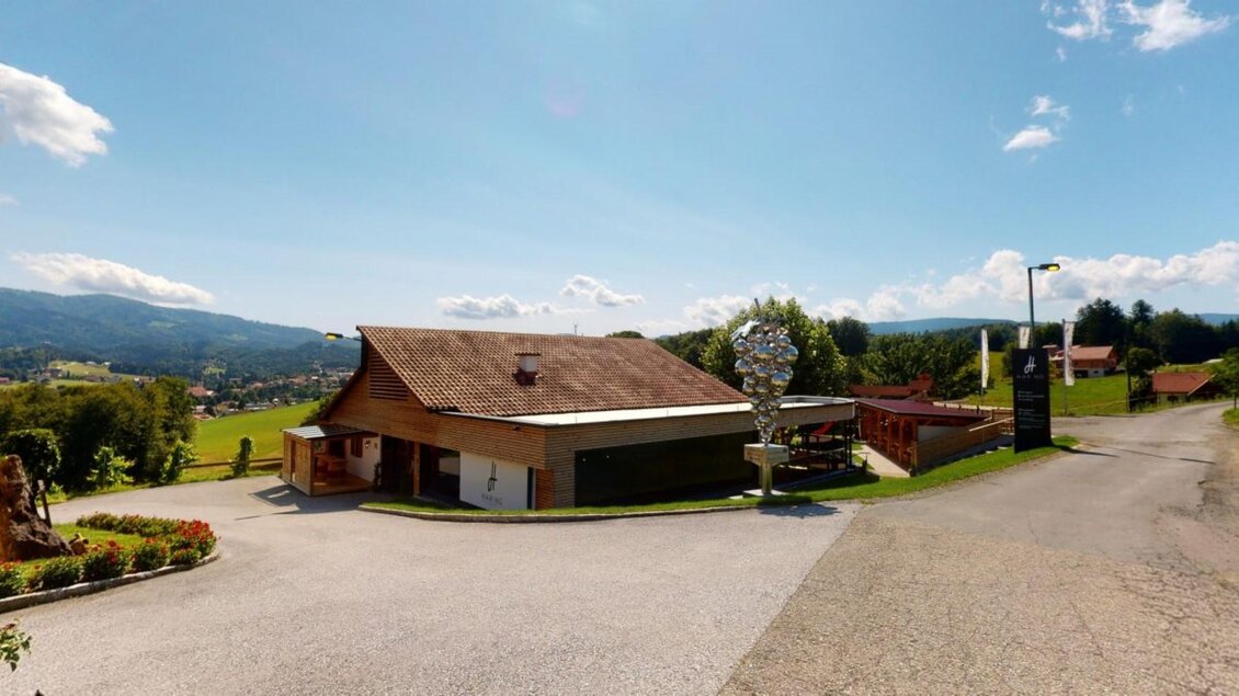 Ein malerisches Gebäude in einer ländlichen Umgebung mit grünen Wiesen und Hügeln im Hintergrund. Der Himmel ist klar und sonnig, was eine einladende Atmosphäre schafft. | © Familie Haring