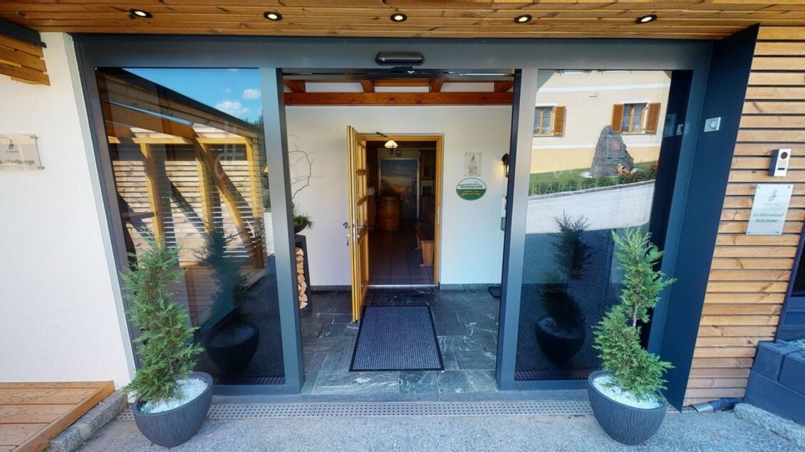 Der Eingangsbereich eines modernen Hauses mit großen Glas Türen. Zu beiden Seiten stehen dekorative Pflanzen in Töpfen. | © Familie Haring