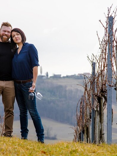 Claudia and Karl with a wine glass and wine bottle in the vineyard. | © Buschenschank Seidl Poidl