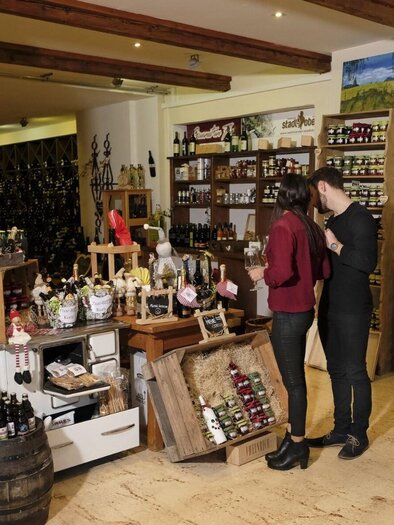 Ein gemütlicher Laden mit Regalen voller lokaler Produkte und Delikatessen. Zwei Personen betrachten gemeinsam die Waren im Geschäft. | © M. Maili