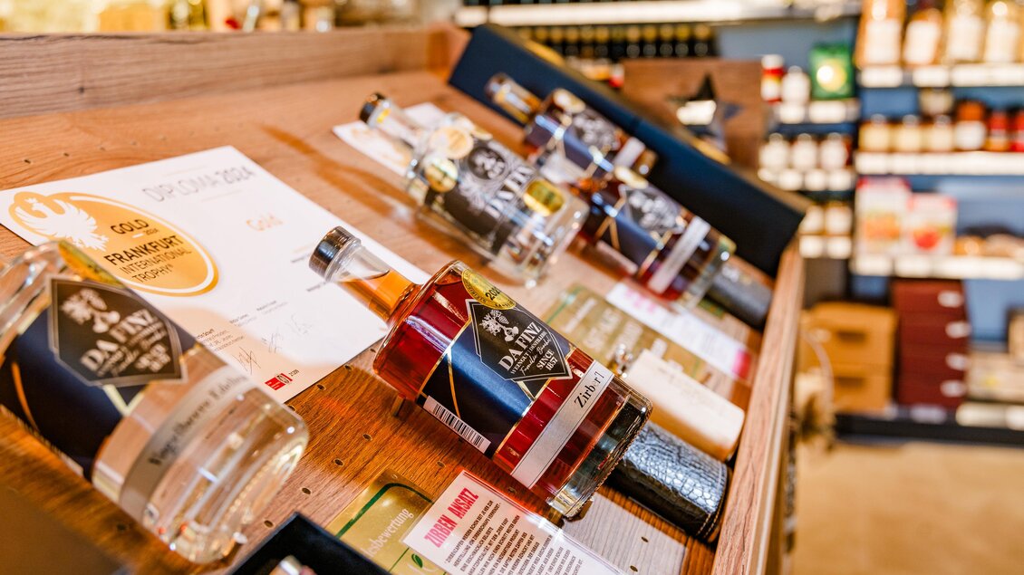 Eine Auslage mit verschiedenen Spirituosenflaschen auf einem Holzregal. Im Hintergrund sind weitere Produkte zu sehen. | © (c) Region Graz - Mias Photoart