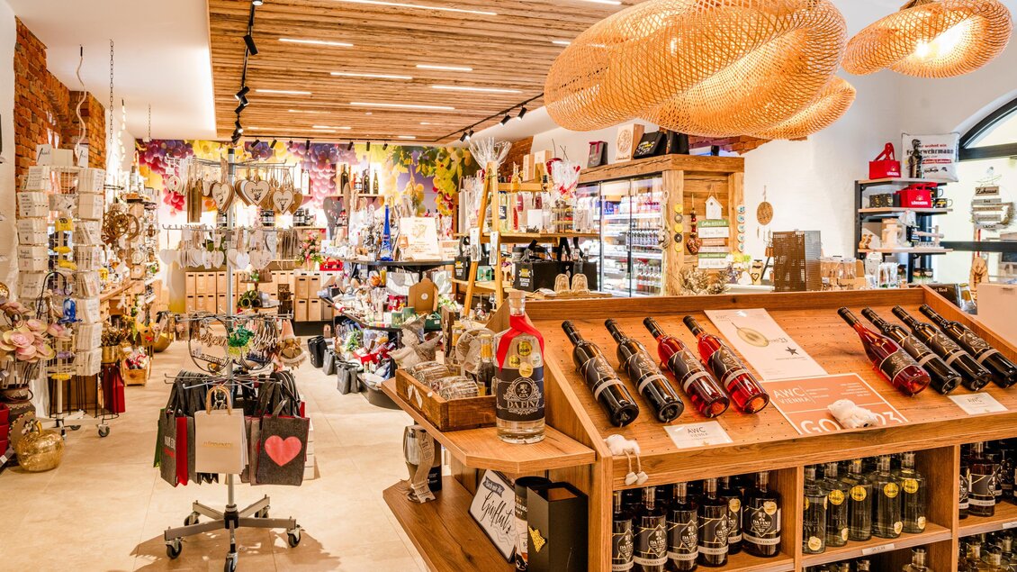 Ein einladendes Geschäft mit vielen Geschenken und Lebensmitteln. Im Vordergrund sind Weine und verschiedene Produkte auf Regalen sichtbar. | © (c) Region Graz - Mias Photoart