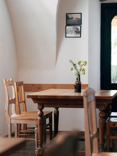 Ein gemütliches Restaurant mit einem Holztisch und Stühlen. Auf dem Tisch steht eine kleine Vase mit Blumen. | © Heldentheater