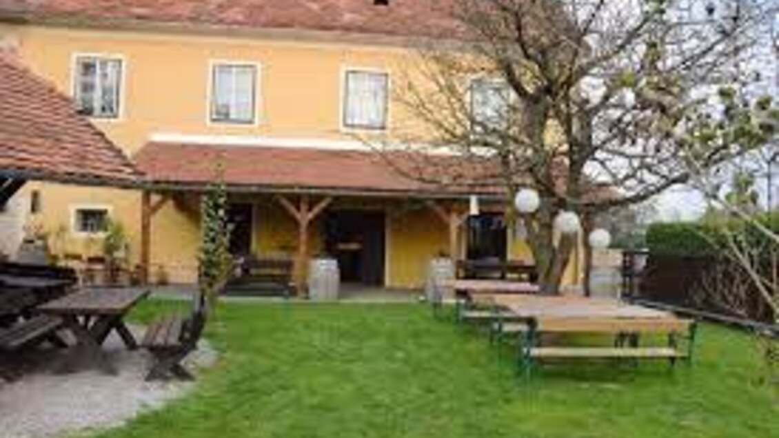 Ein gemütlicher Garten mit Bänken und Tischen vor einem gelben Gebäude. Der Raum ist einladend und ideal für gesellige Zusammenkünfte. | © Buschenschank Habersack