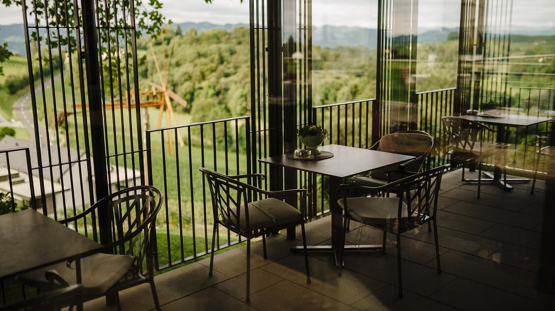 Ein elegantes Restaurant mit großen Fenstern und Blick auf die grüne Landschaft. Die Tische sind für Gäste vorbereitet und schaffen eine einladende Atmosphäre. | © Weinrefugium Brolli