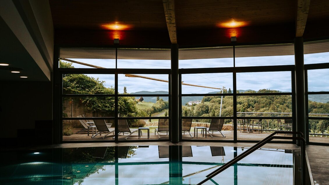 Ein moderner Innenpool mit großen Fenstern, die eine schöne Aussicht auf die grüne Landschaft bieten. Der Raum ist hell und einladend, ideal zum Entspannen. | © Weinrefugium Brolli