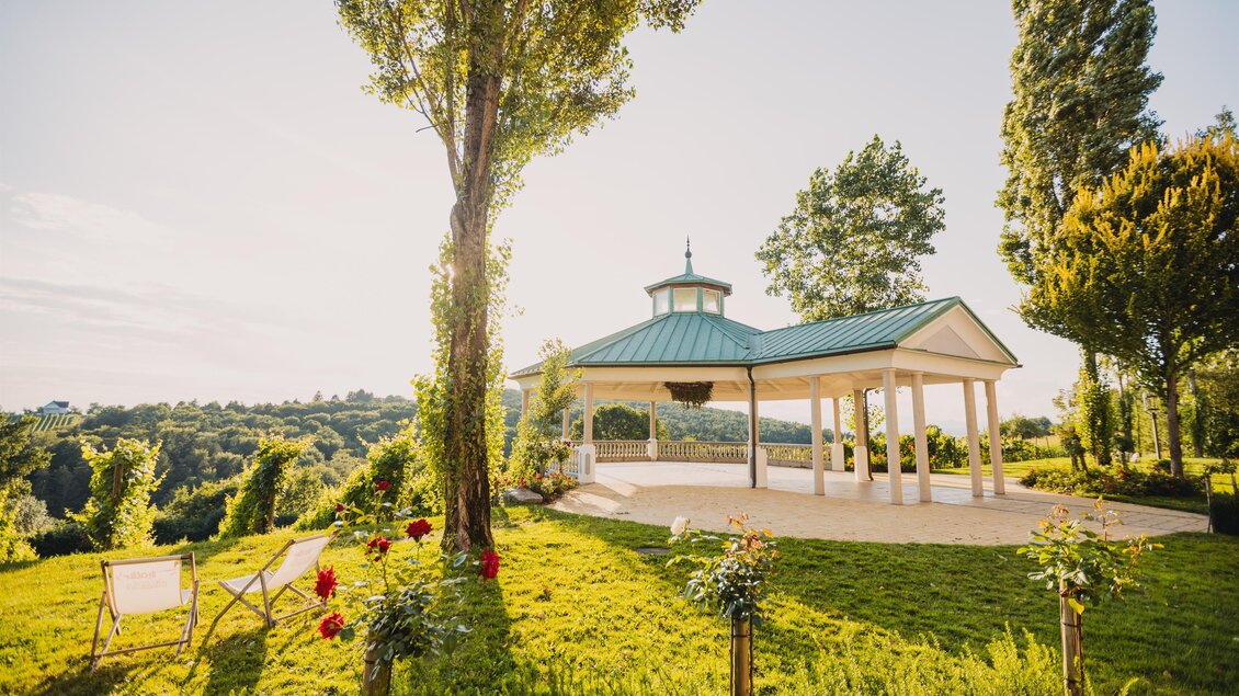 Ein schöner Pavillon auf einer grünen Wiese. Umgeben von Bäumen und Blumen bietet er einen herrlichen Ausblick auf die Landschaft. | © Weinschloss Thaller
