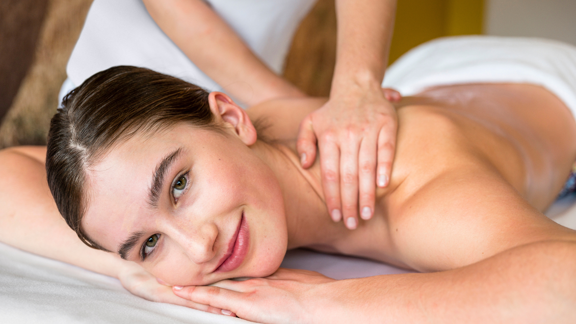 Eine entspannte Person bekommt eine Massage. Sie lächelt freundlich und genießt die Behandlung. | © Aldiana GmbH
