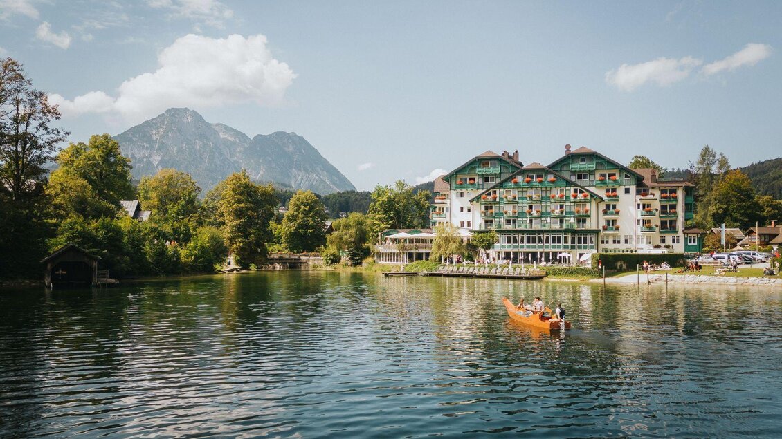 Ein schöner See umgeben von Bäumen und Bergen. Im Vordergrund fährt ein Boot auf dem Wasser vorbei. | © Karl Steinegger