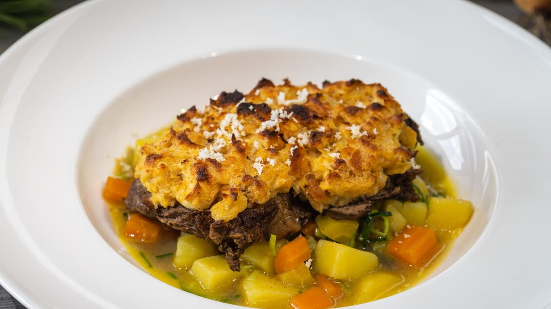 Ein köstliches Gericht mit zartem Fleisch, bedeckt mit einer goldbraunen Kruste. Dazu gibt es buntes Gemüse in einer aromatischen Brühe. | © martin huber
