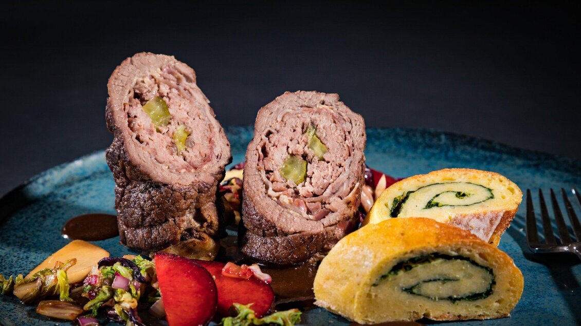 Ein stilvoll angerichteter Teller mit gefülltem Fleisch und einem bunten Beilagensalat. Daneben liegt eine Schnecke aus Röllchen mit Spinat. | © J. Laban - Werner Krug