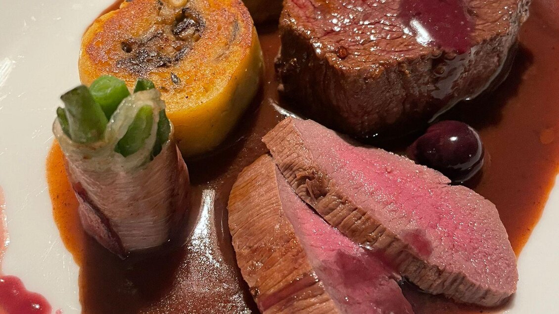 Ein kunstvoll angerichteter Teller mit zartem Fleisch, buntem Gemüse und einer roten Sauce. Das Gericht sieht sehr appetitlich aus und präsentiert verschiedene Texturen und Farben. | © Andreas Wieser