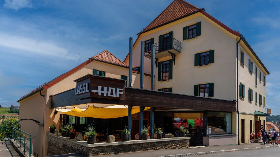 Ein charmantes Restaurantgebäude mit einem einladenden Eingang und Tischen im Freien. Der Himmel ist klar und blau, was eine angenehme Atmosphäre vermittelt. | © Linshalm Fotografie