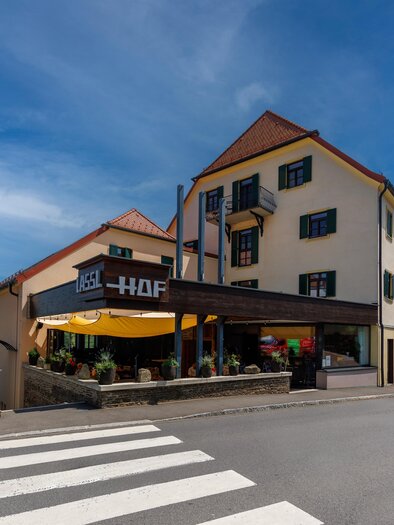 A charming restaurant building with an inviting entrance and outdoor tables. The sky is clear and blue, creating a pleasant atmosphere. | © Linshalm Fotografie