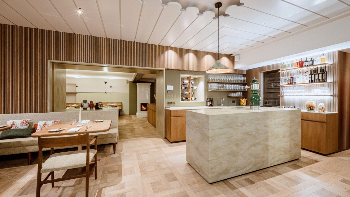 Ein modernes Restaurant mit einem eleganten Empfangstresen aus Stein. Die Einrichtung ist minimalistisch mit warmen Holzdetails und einer gemütlichen Atmosphäre. | © Christoph Huber