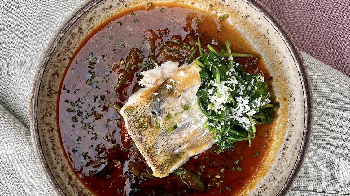 Eine Schüssel mit einer reichhaltigen Suppe, garniert mit Fisch und frischem Spinat. Die Farben sind lebhaft und ansprechend. | © Lisa Ell-Mayer