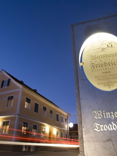 Ein gemütliches Weinhaus mit einladendem Schild bei Dämmerlicht. Die Architektur ist traditionell und ansprechend. | © Bergmann